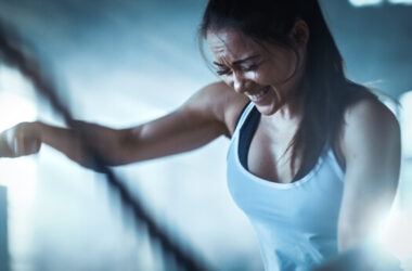 Eine Frau beim intensiven HIIT-Training, in ihrem Gesicht ist deutliche Anstrengung sichtbar.