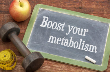Eine Tafel mit der Aufschrift Boost your metabolism, daneben ein Apfel und eine Hantel.